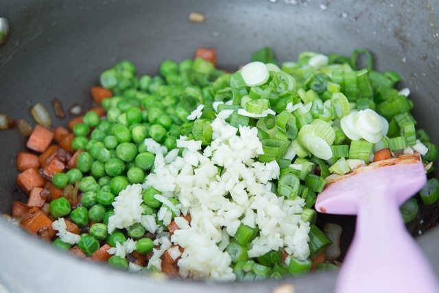 Adding peas, garlic, and scallions to Cauliflower Chicken Fried Rice